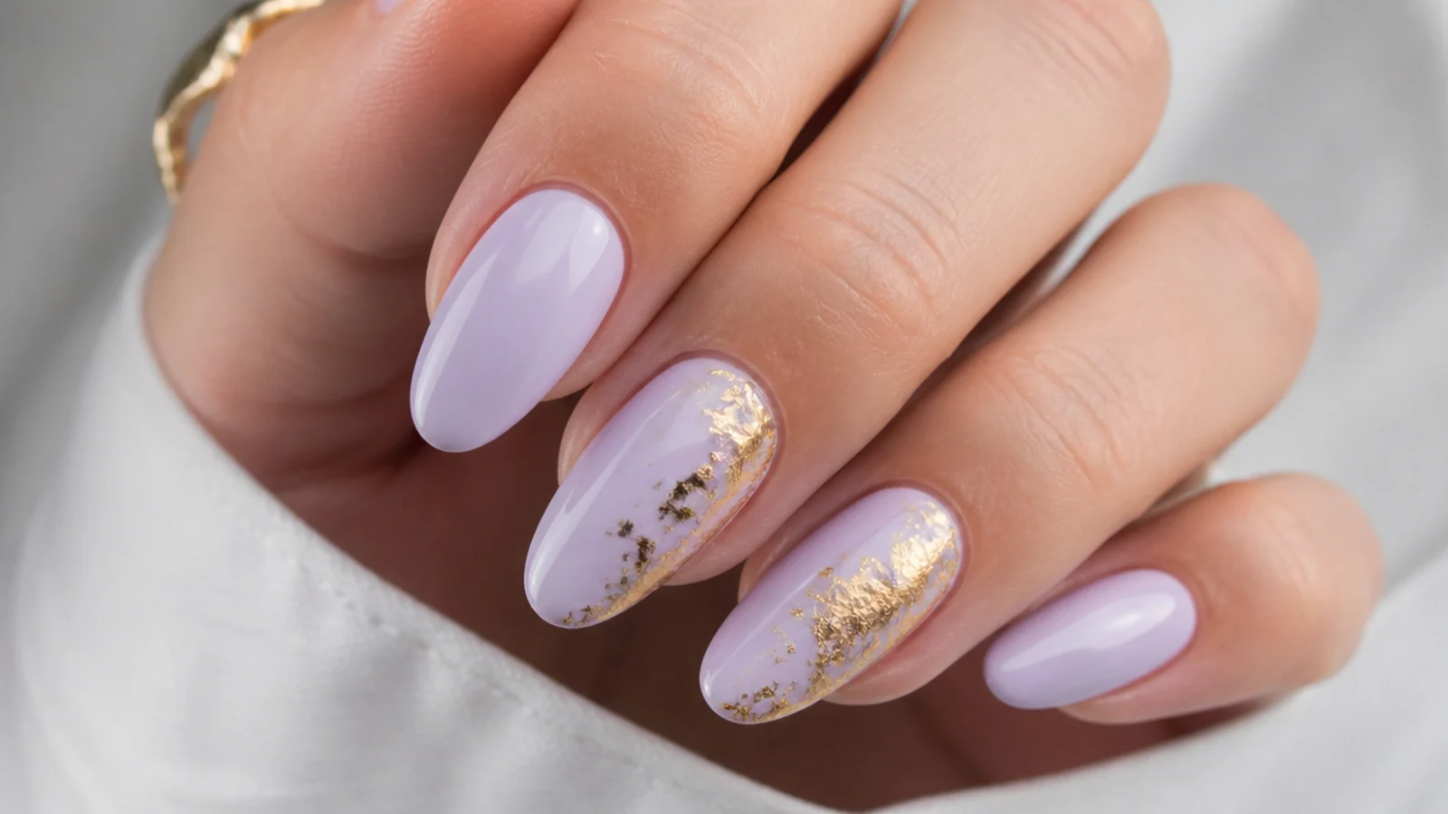 Milky lavender nails with torn gold foil accents on two nails