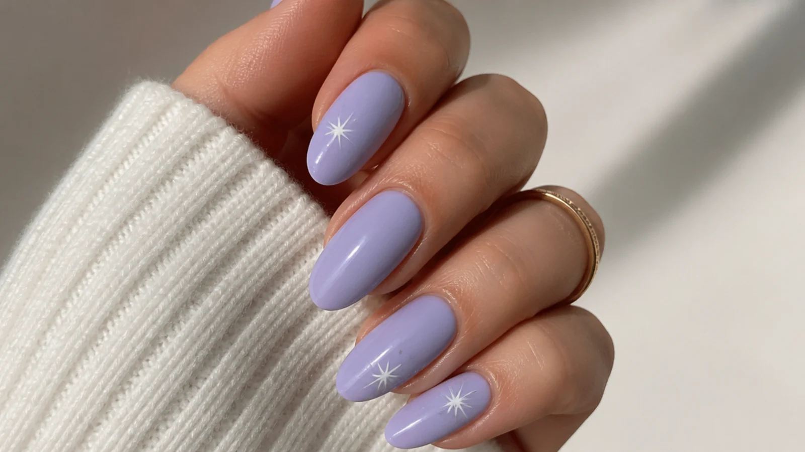 Soft milky lavender nails on an almond shape against a neutral background