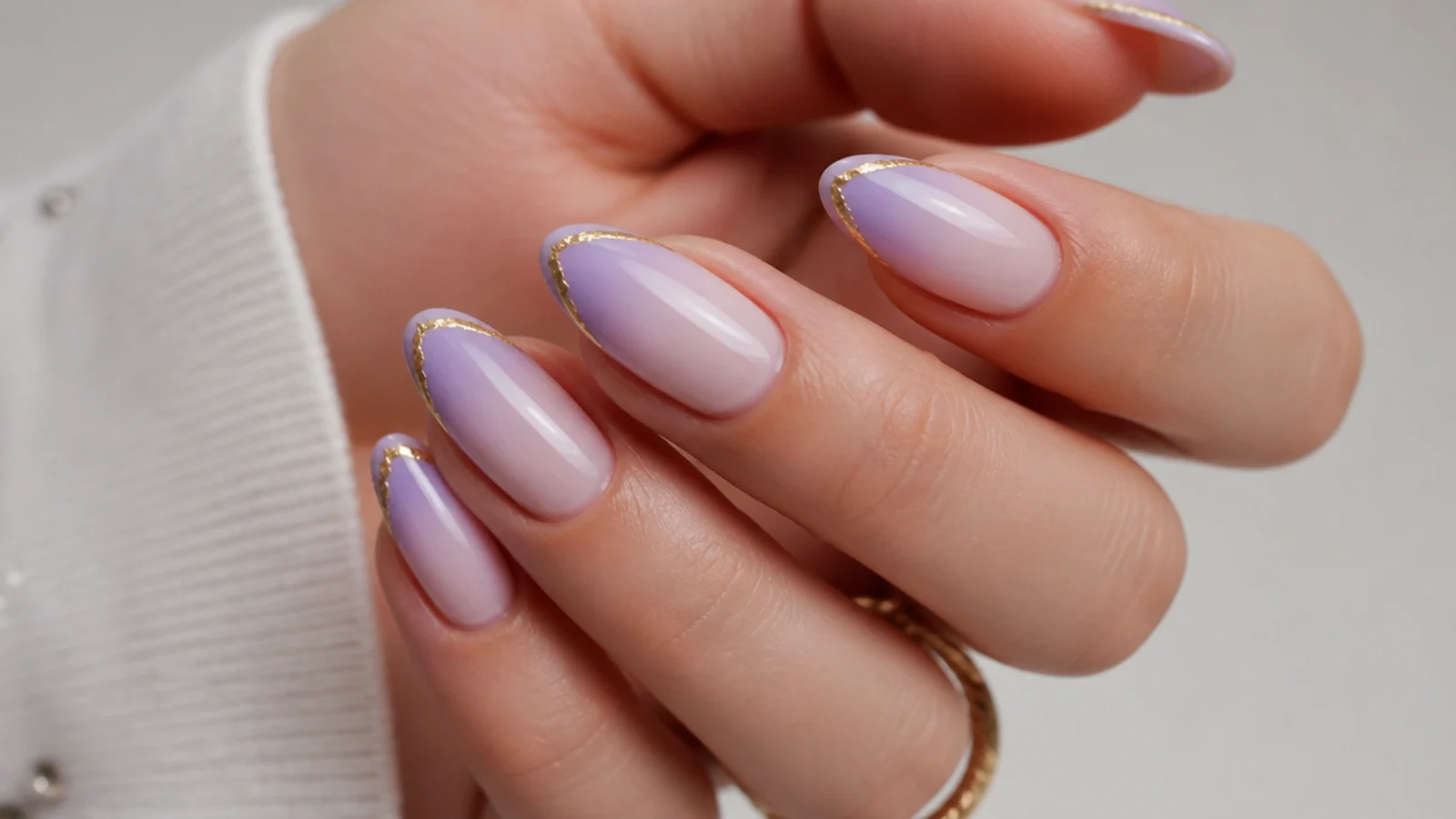 Lavender ombre nails with a thin gold foil line at the tip on almond nails