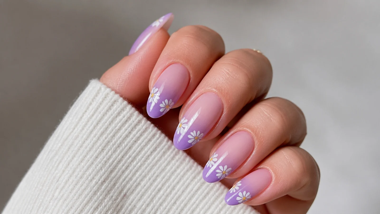 Lavender ombre nails with small white daisy accents near the tips on almond nails