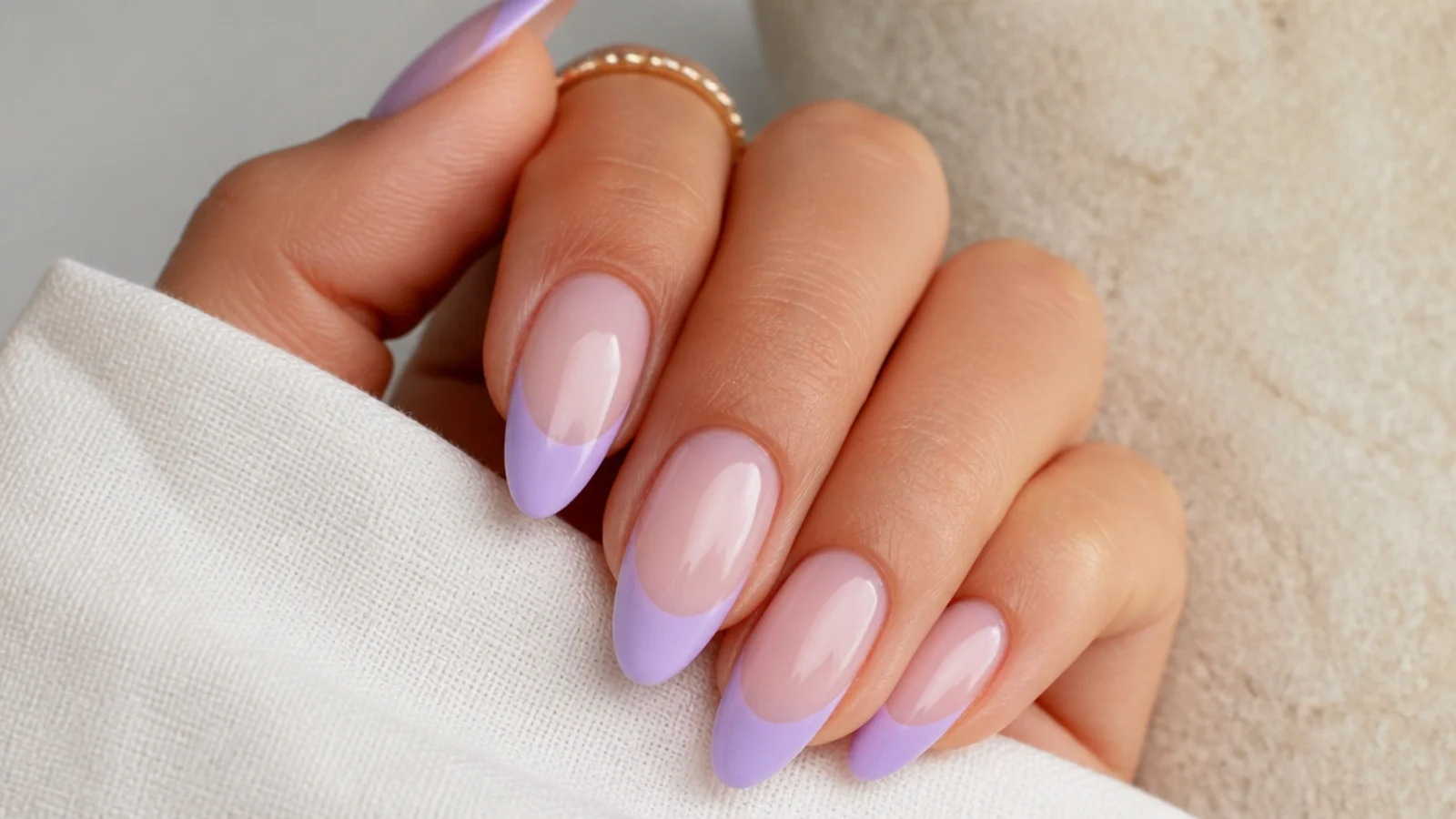 Milky nude nails with soft lavender French tips on an almond shape