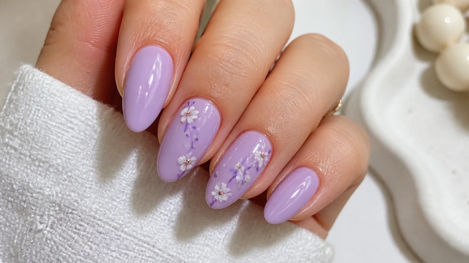 Soft lavender spring nails on an almond shape with tiny white floral accents