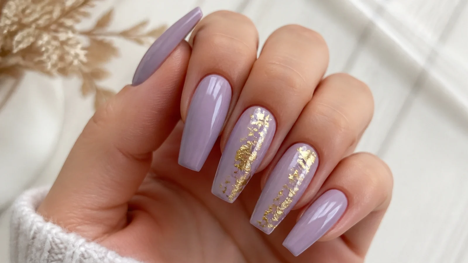 Light lavender nails with delicate gold foil accents on two coffin nails