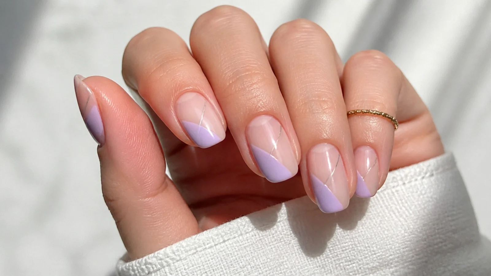 Bare glossy nails with milky lavender geometric shapes over negative space