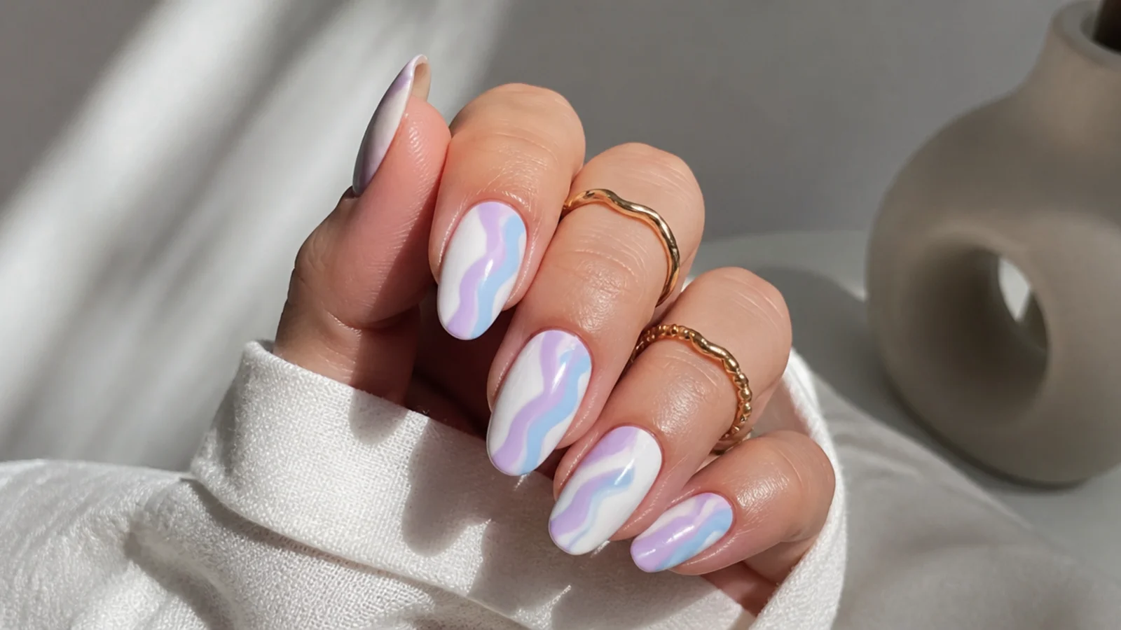 Pastel lavender and baby blue swirl nails on white, almond shape