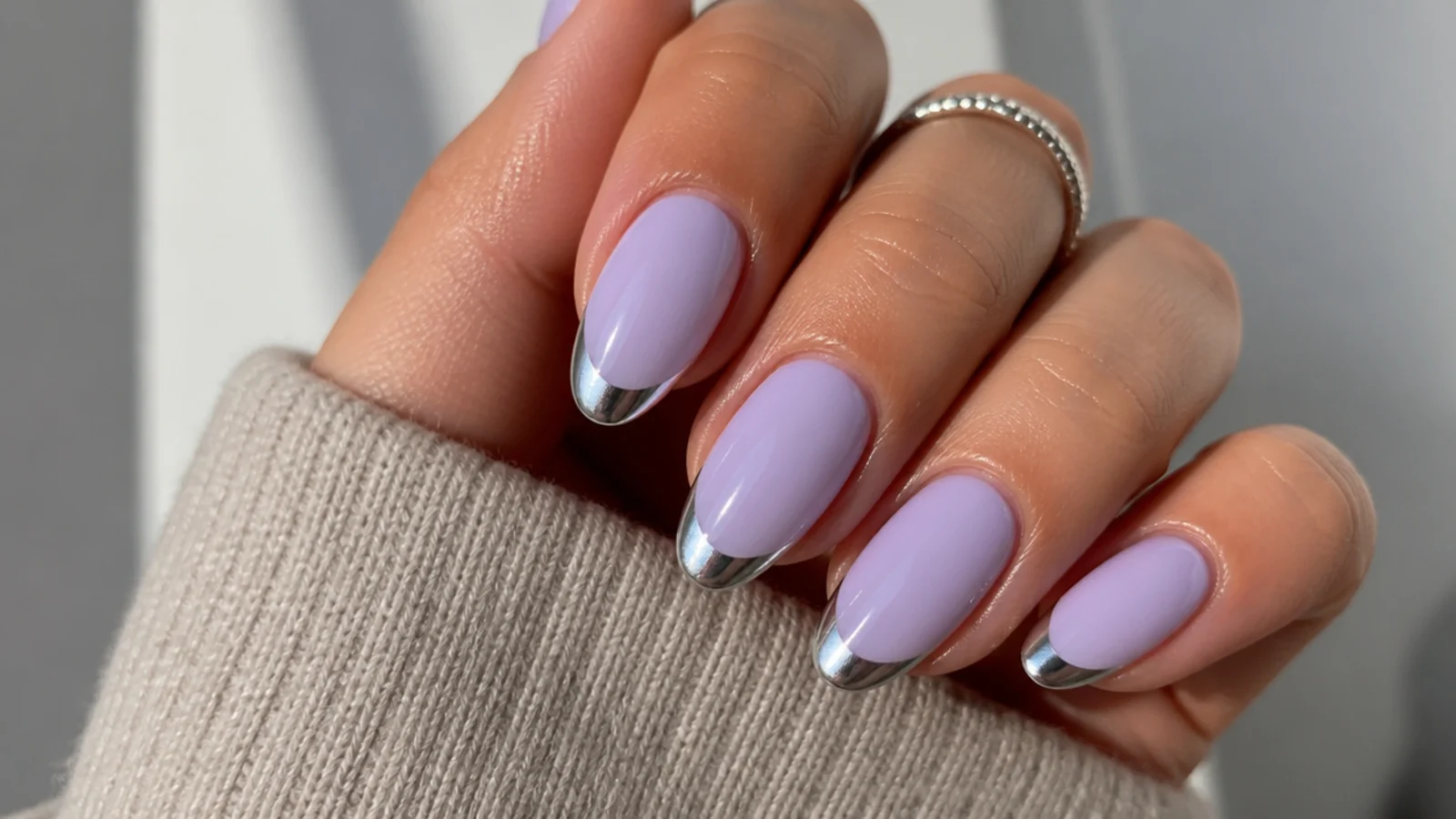 Milky lavender nails with reflective silver chrome tips, almond shape