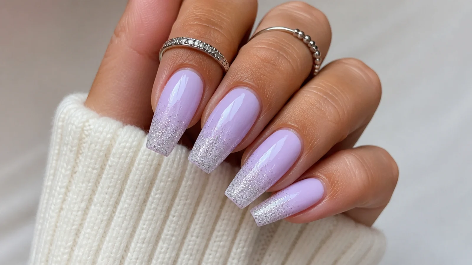 Milky lavender nails with fine silver glitter fading from the tips, coffin shape
