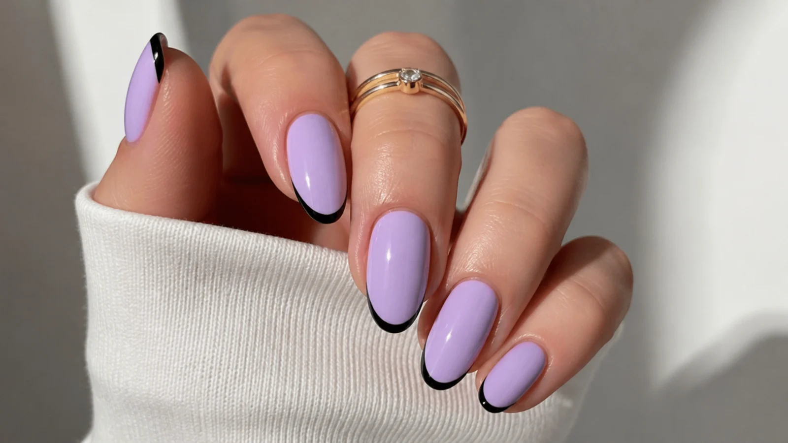 Soft lilac nails with a thin black French line accent