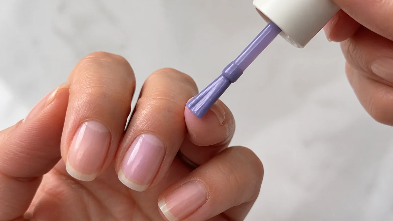 A thin first coat of light purple gel painted over a prepped nail