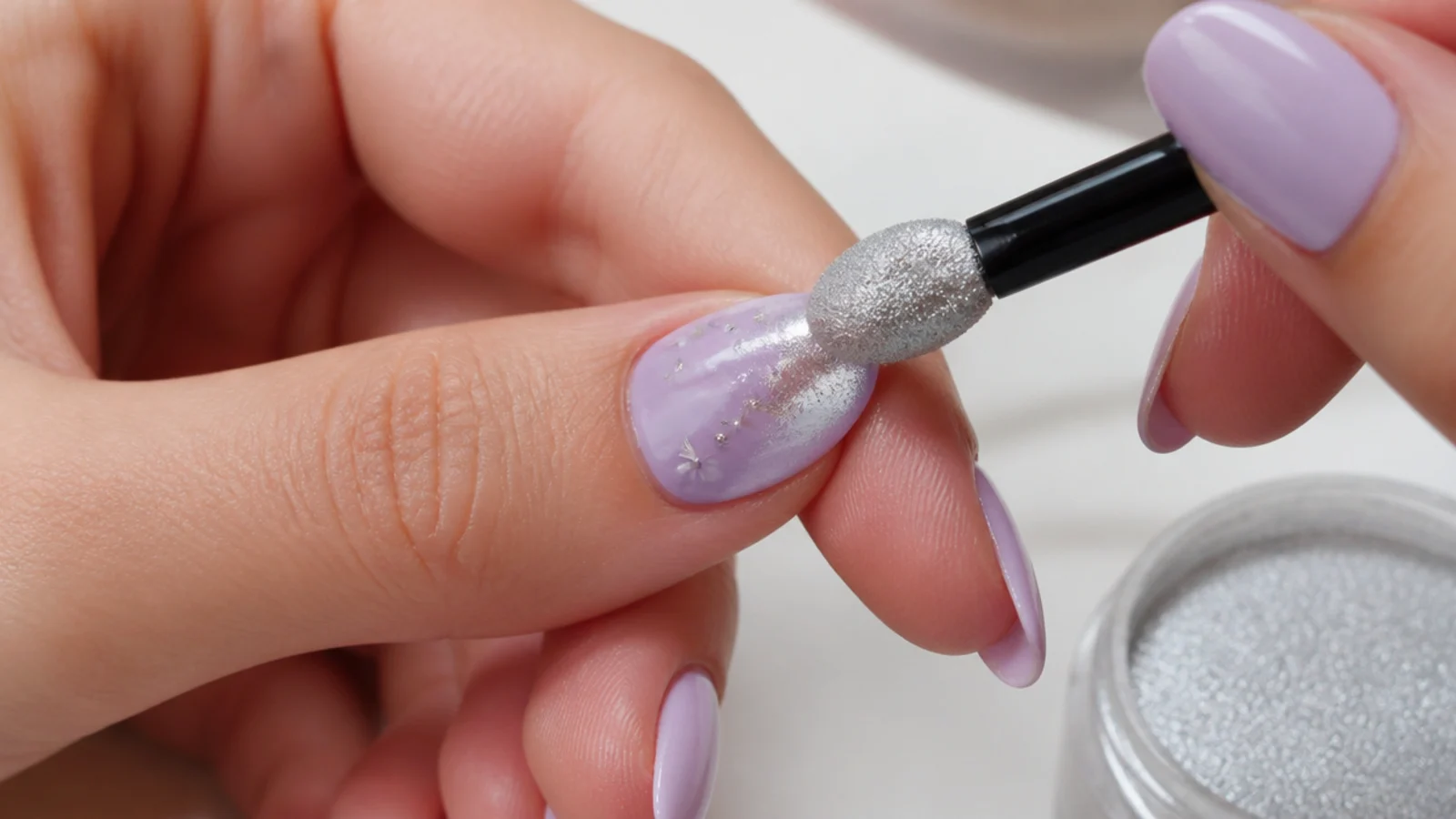 Silver chrome powder being buffed over a cured light purple accent nail