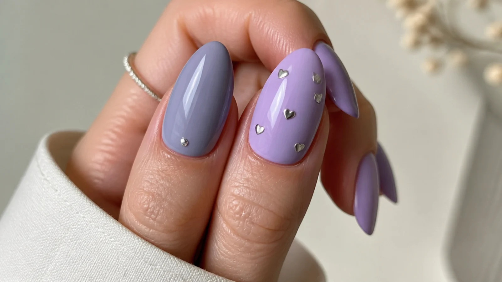 A soft gray-blue lavender nail next to a broader pastel light purple nail