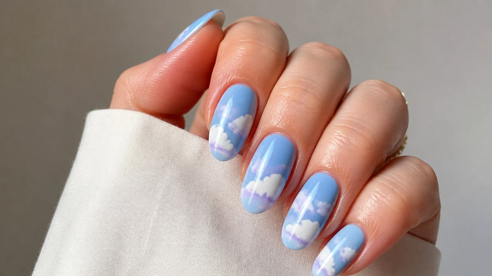 Soft blue sky nails with fluffy white and lilac clouds
