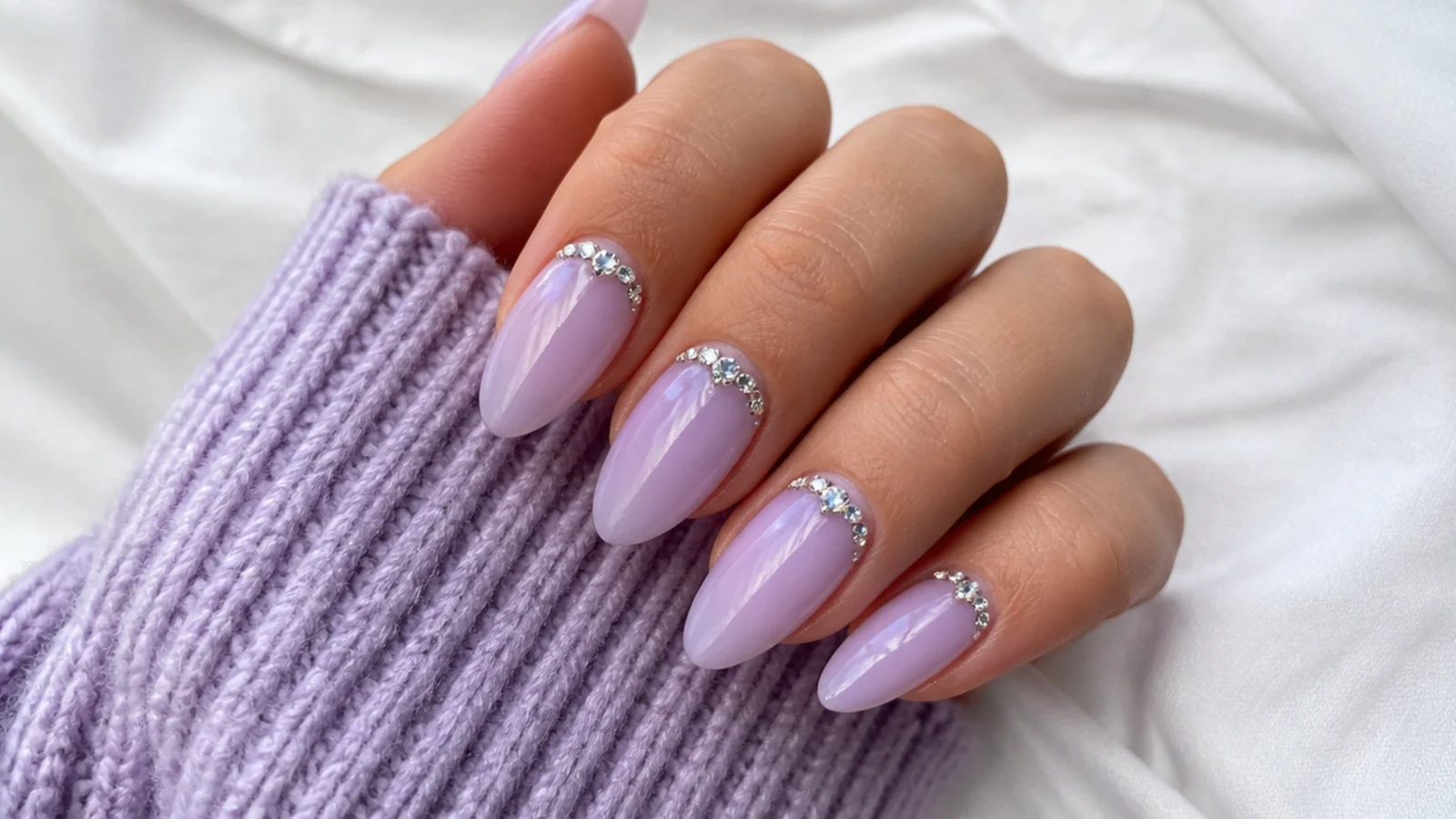 Milky lilac acrylic nails with a cluster of clear rhinestones near the cuticle