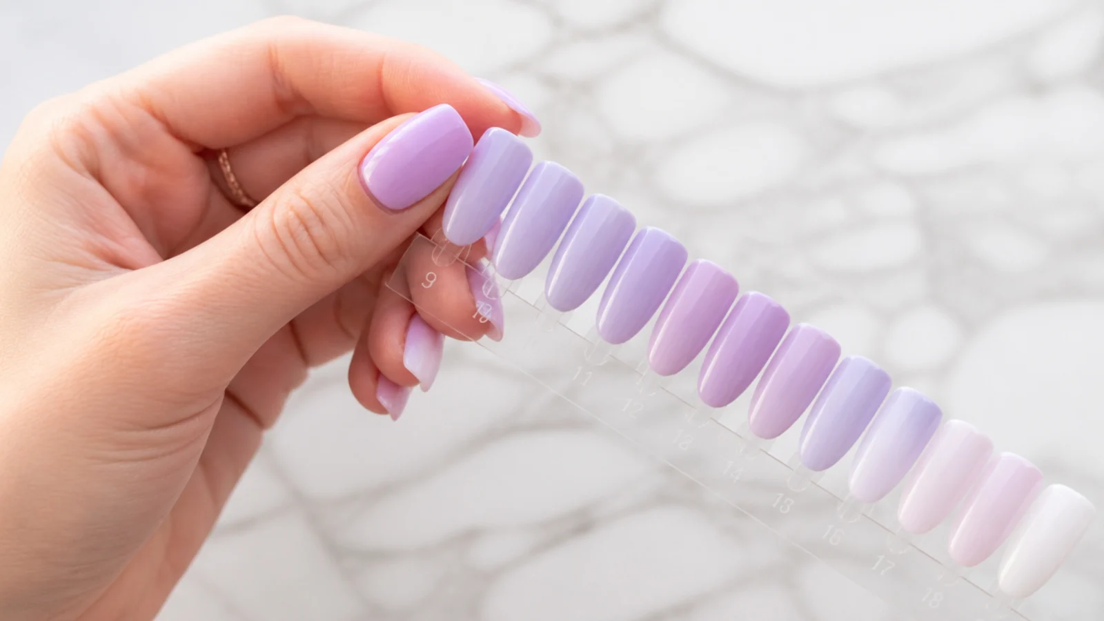 Swatching several light purple gels on a nail tip to match the exact shade