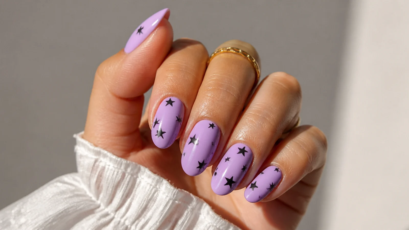 Pastel lilac nails scattered with small black star shapes
