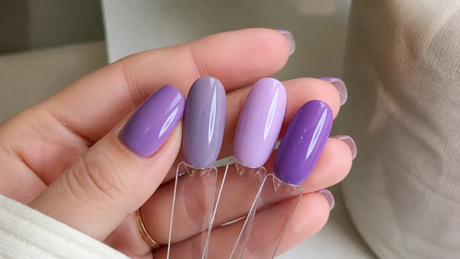 A grayed lavender swatch beside a pastel lilac and a violet on nail tips