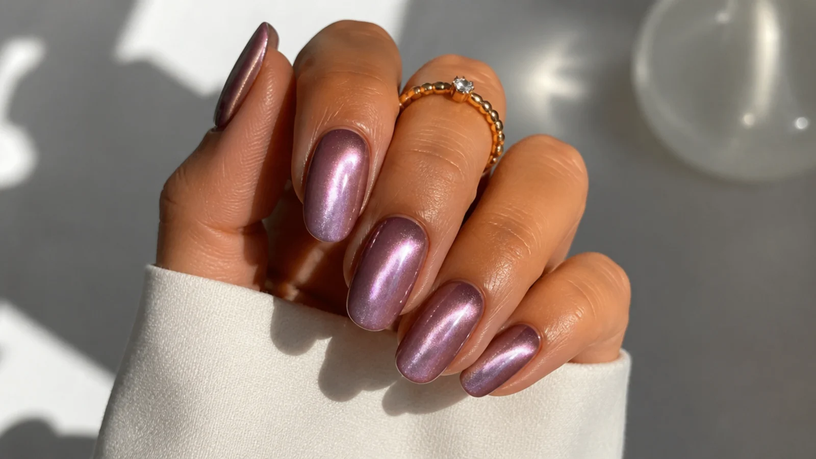 Warm pink-toned light purple cat eye nails with a bright beam on tan skin