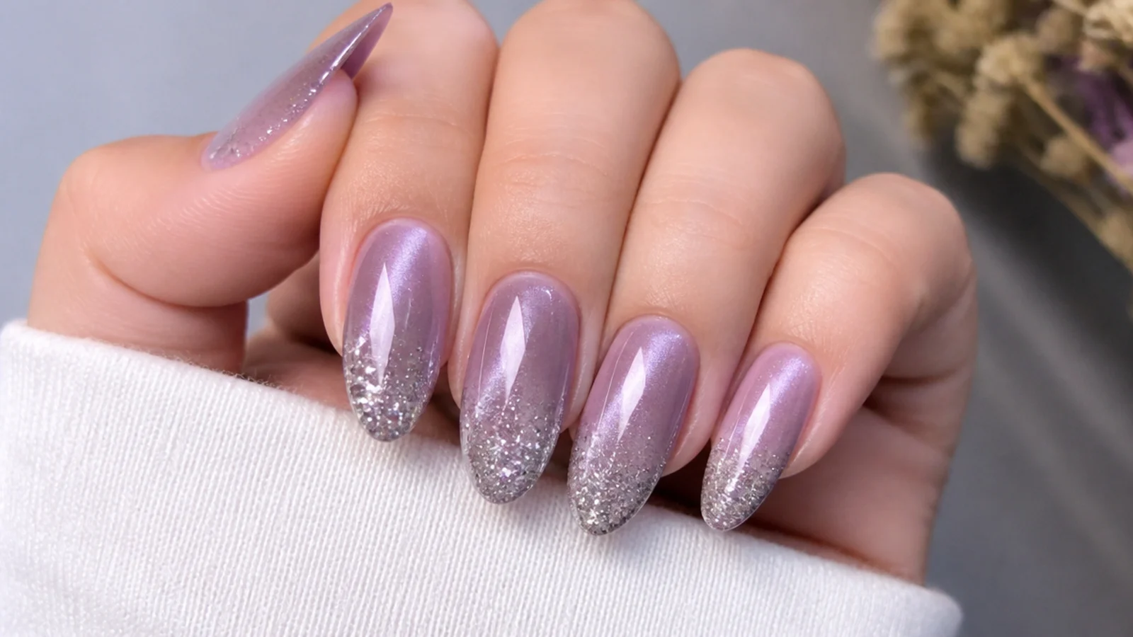 Light purple cat eye nails fading into silver glitter at the tips