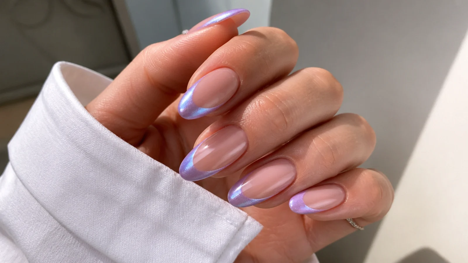 Sheer nails with lilac chrome French tips on an almond shape