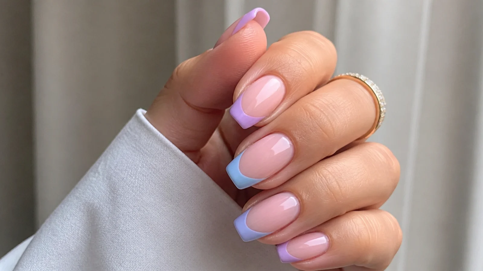 Alternating light purple and light blue french tips across a nude hand