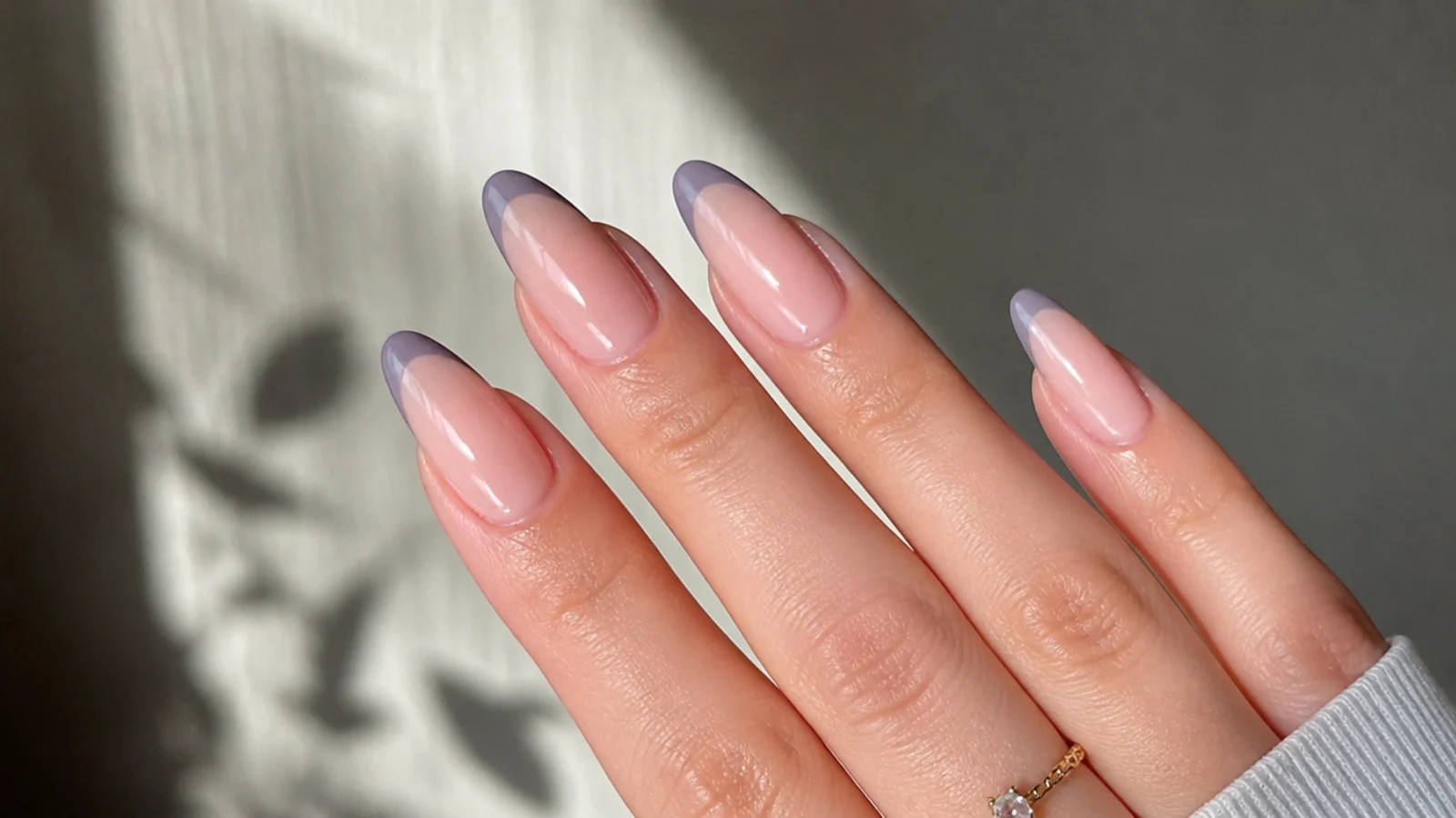 Greyed lilac french tips on long almond nails over a nude base