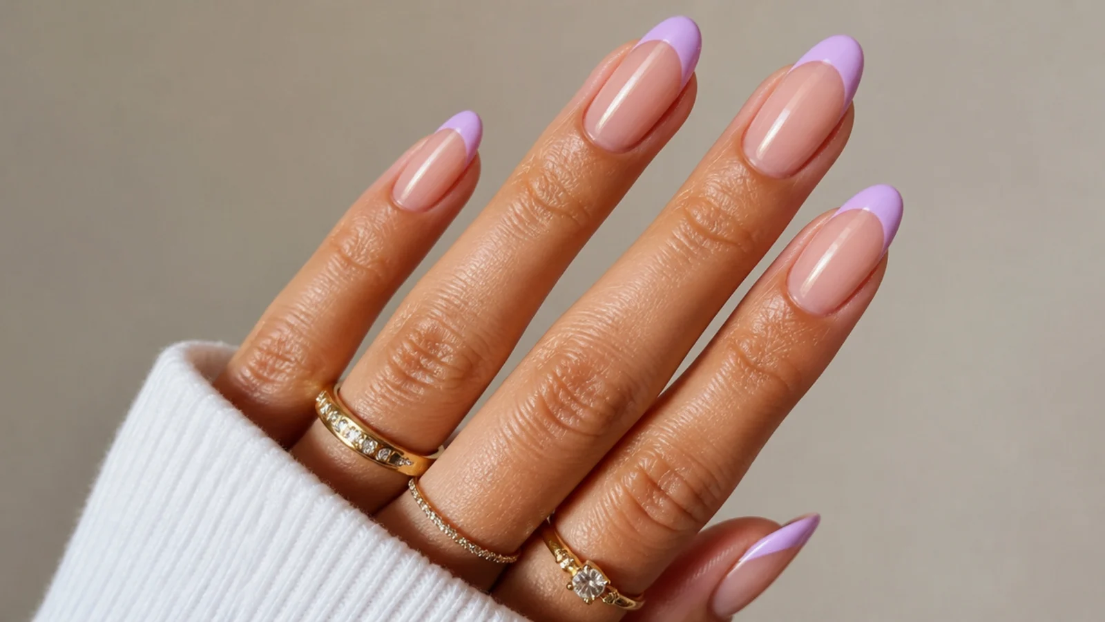 Warm pink-lilac french tips on medium-tan skin over a nude base