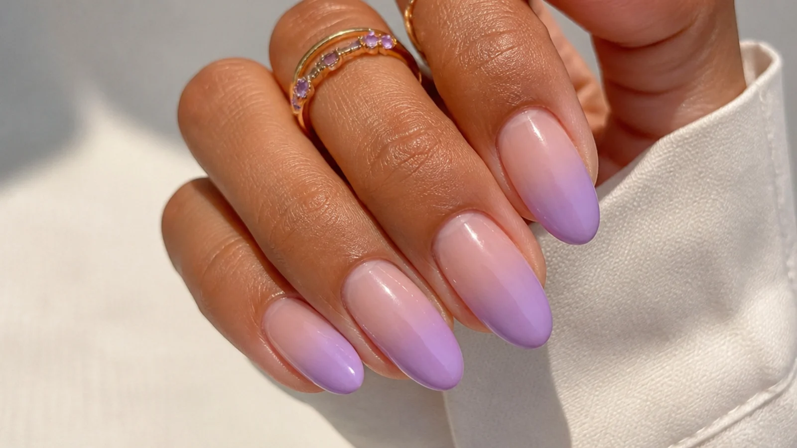 Warm pink-based lilac ombre nails fading to nude on medium skin