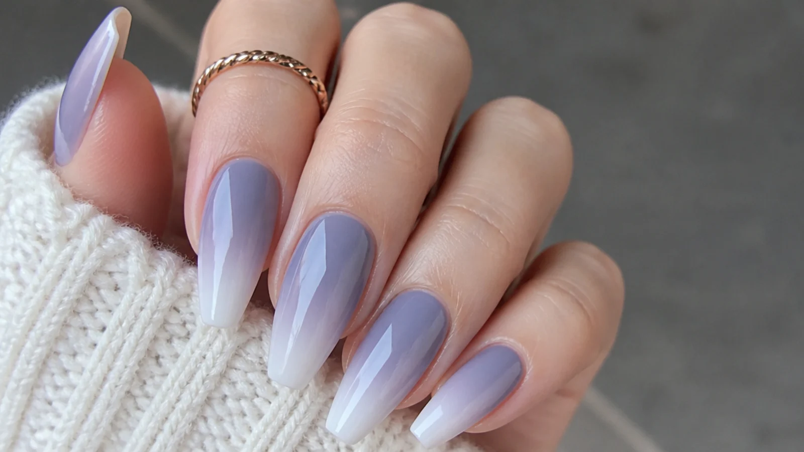 Muted gray-lilac ombre nails fading to soft white on a coffin shape