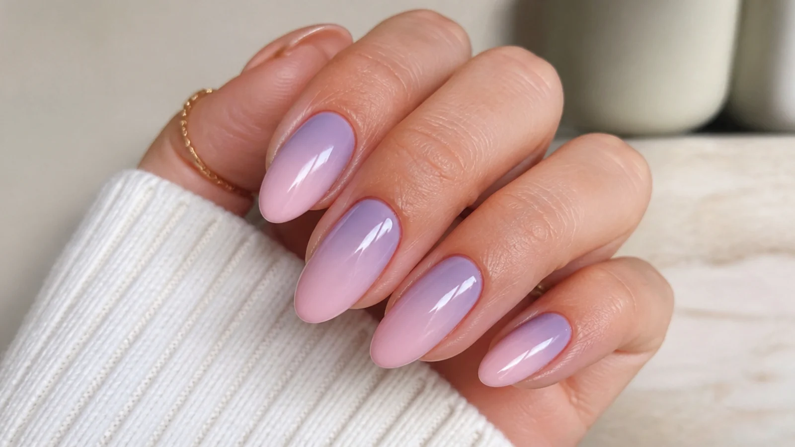 Light purple fading into soft pink ombre nails on an almond shape