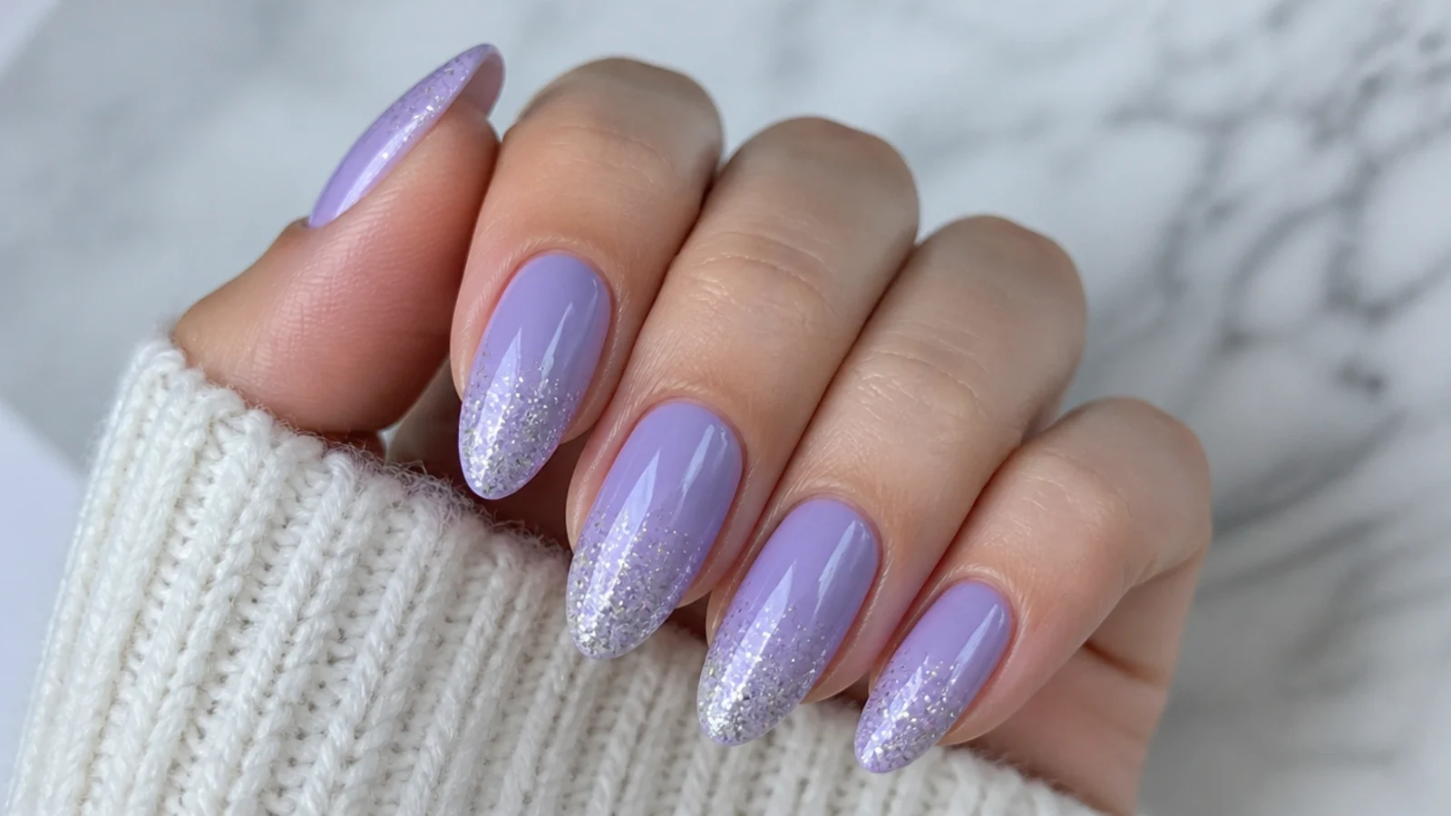 Lilac nails with silver glitter ombre fading from the tip on almond nails