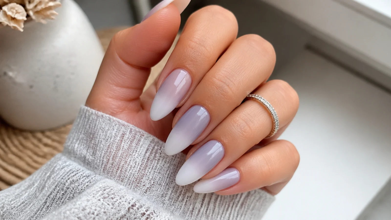 Soft gray-lavender ombre nails fading to white on a long almond shape