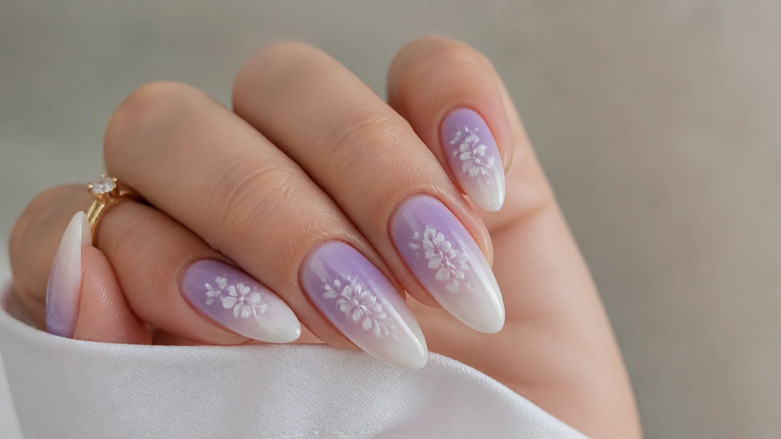 Lilac to white ombre nails with small white floral accents on almond