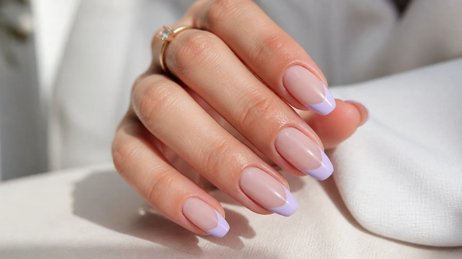 Sheer nude nails with soft lavender French tips on an almond shape