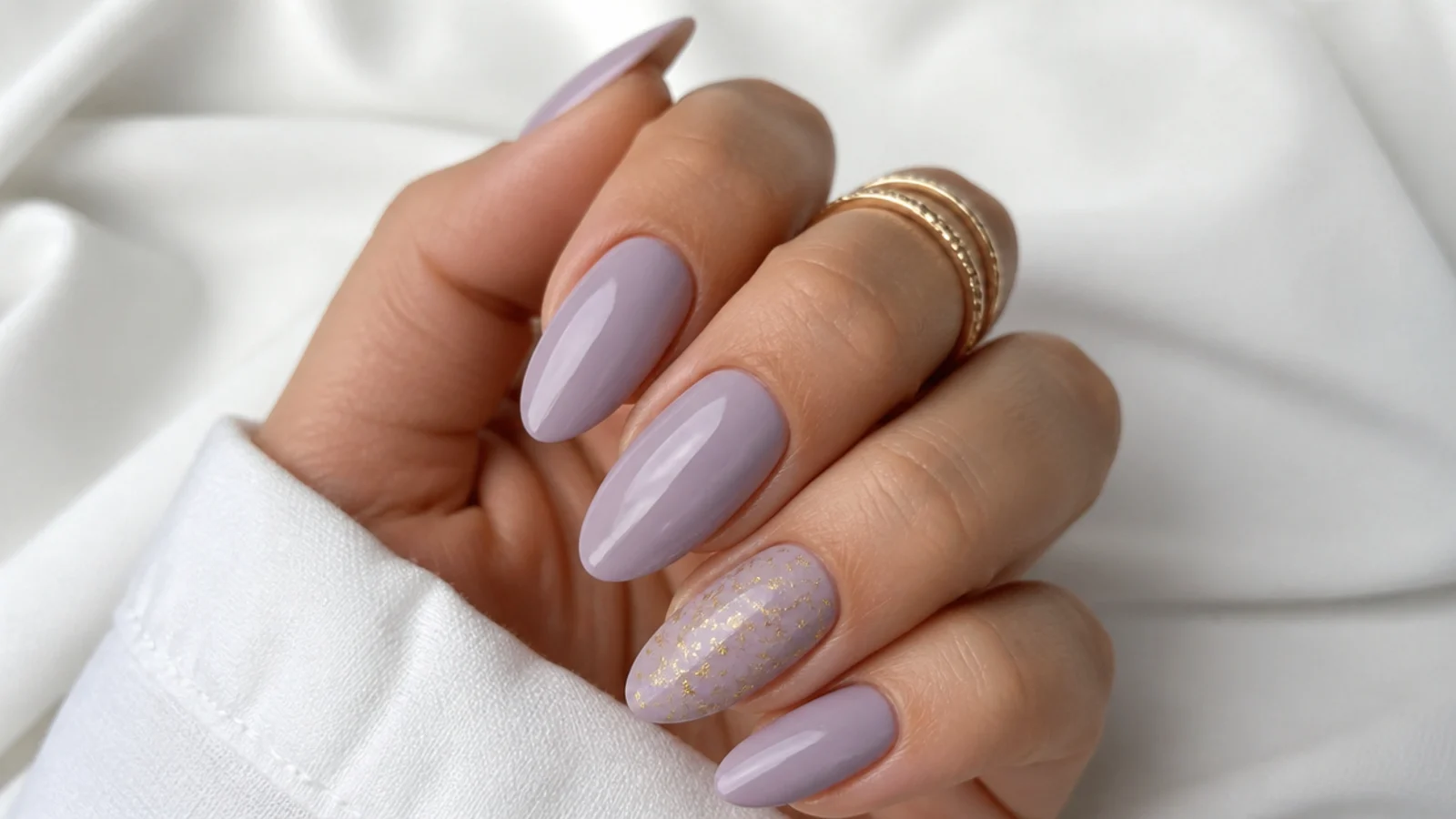 Light purple nails with thin gold foil flakes on an accent nail