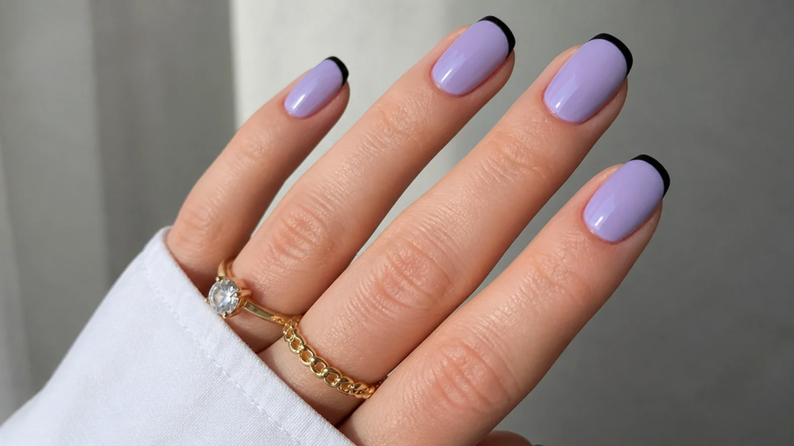 Soft light purple nails with a thin black French line for contrast