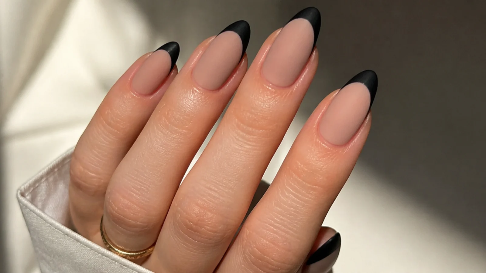 Nude matte nails with black matte French tips on an almond shape