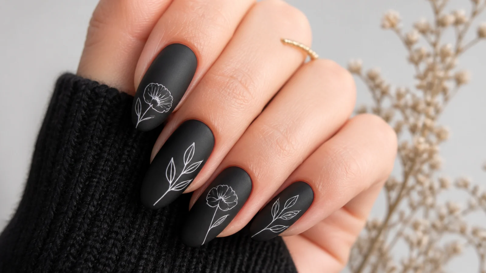 Matte black nails with delicate white line-drawn flowers