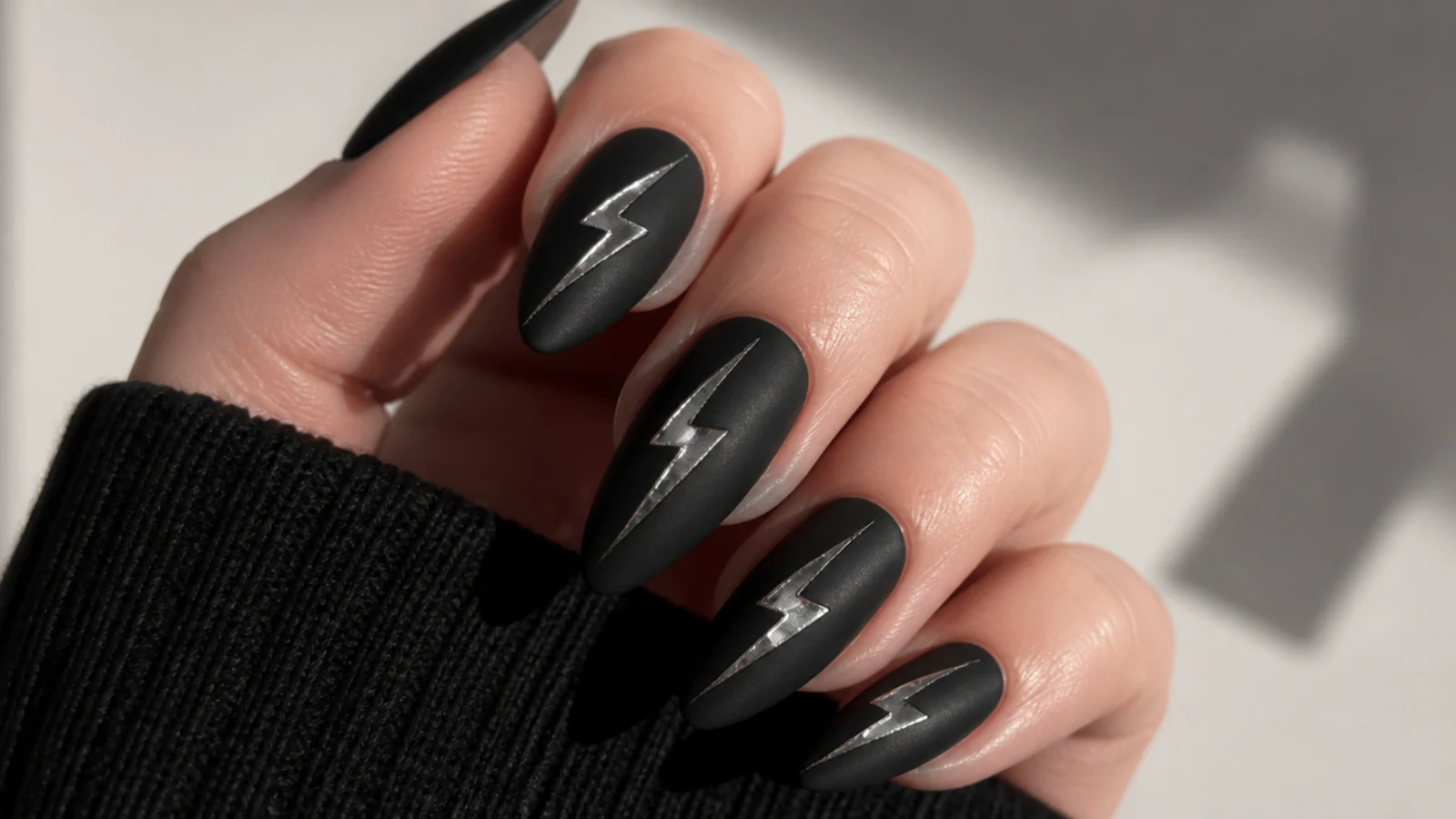 Matte black nails with silver chrome lightning bolt streaks