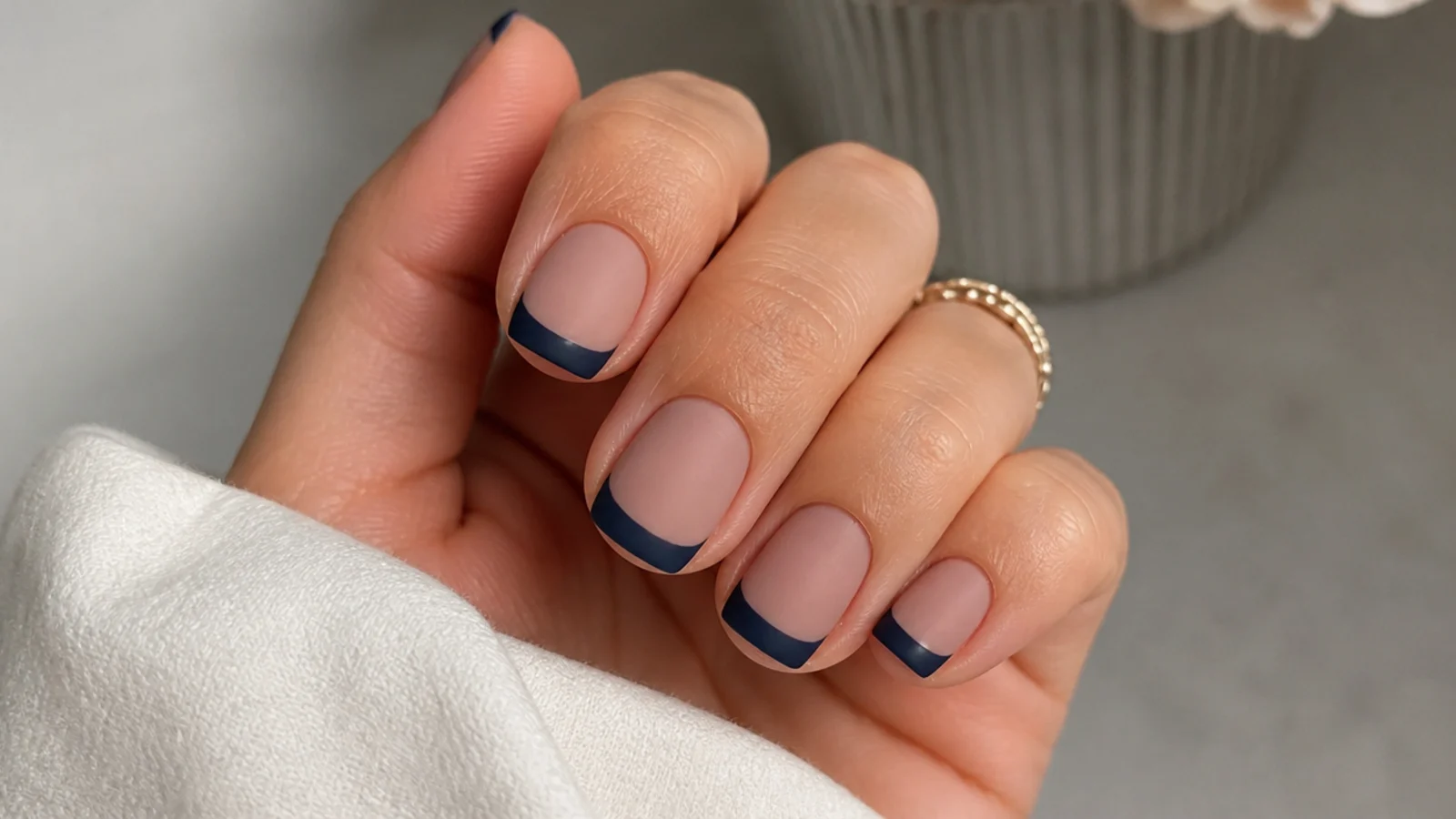 Matte navy French tip nails on a nude base, short squoval shape