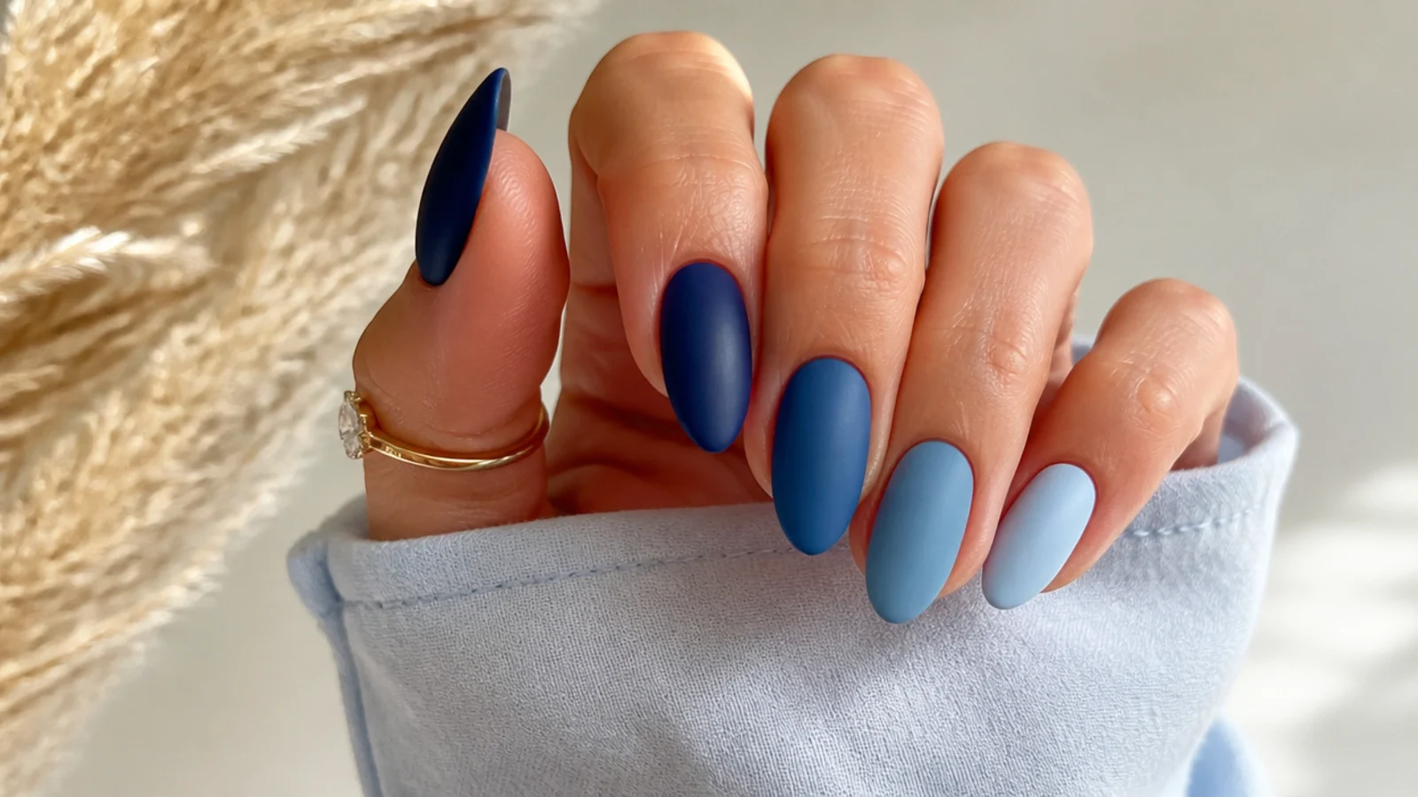 Matte blue ombre nails fading navy to pale ice across the hand