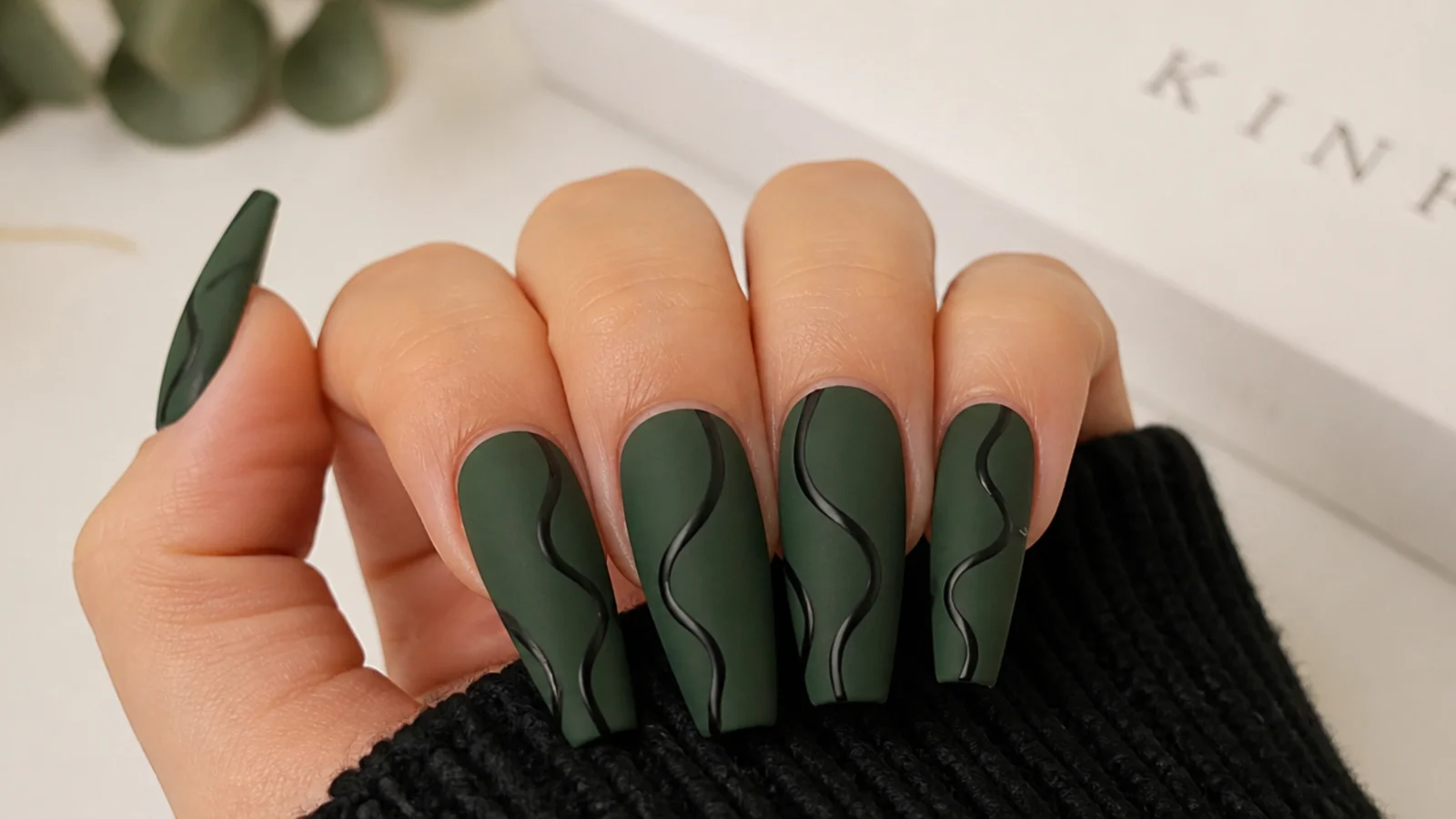 Matte forest green nails with black abstract swirls on coffin nails
