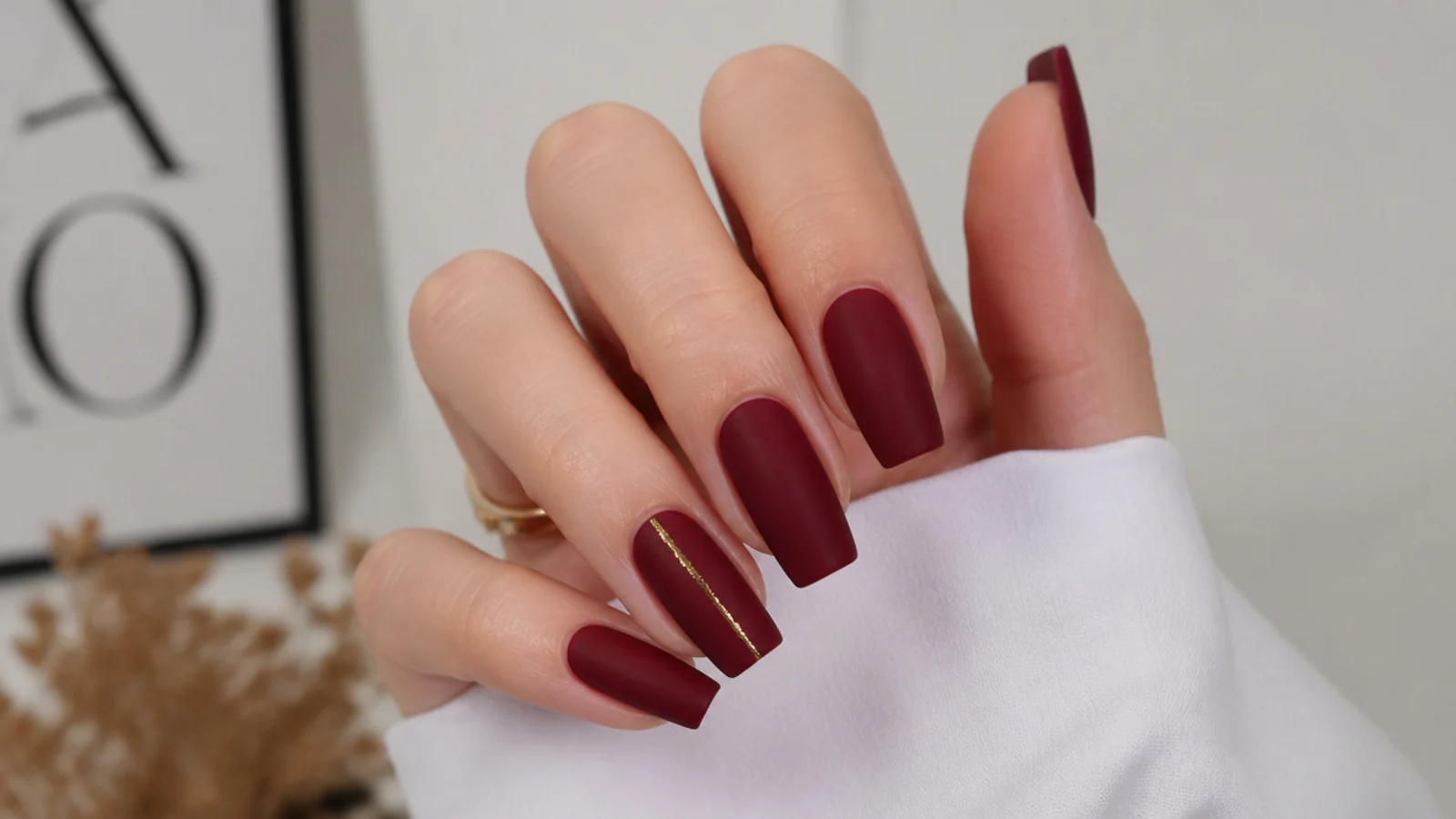 Matte merlot red nails with one thin glossy gold foil accent