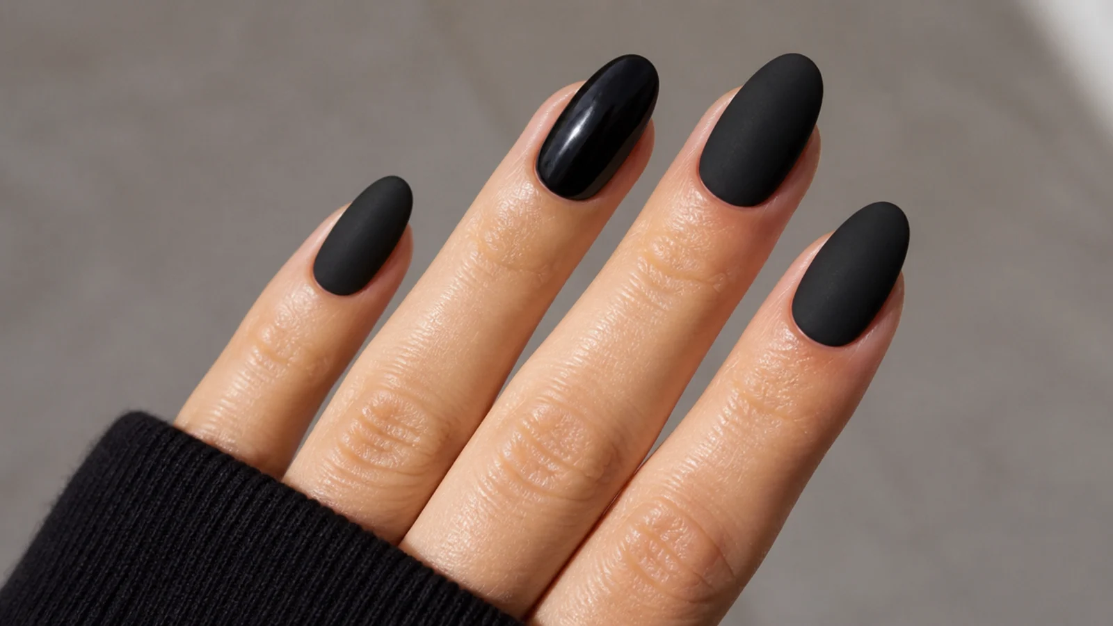 Velvety matte black nails on an almond shape with one shiny grease patch for comparison