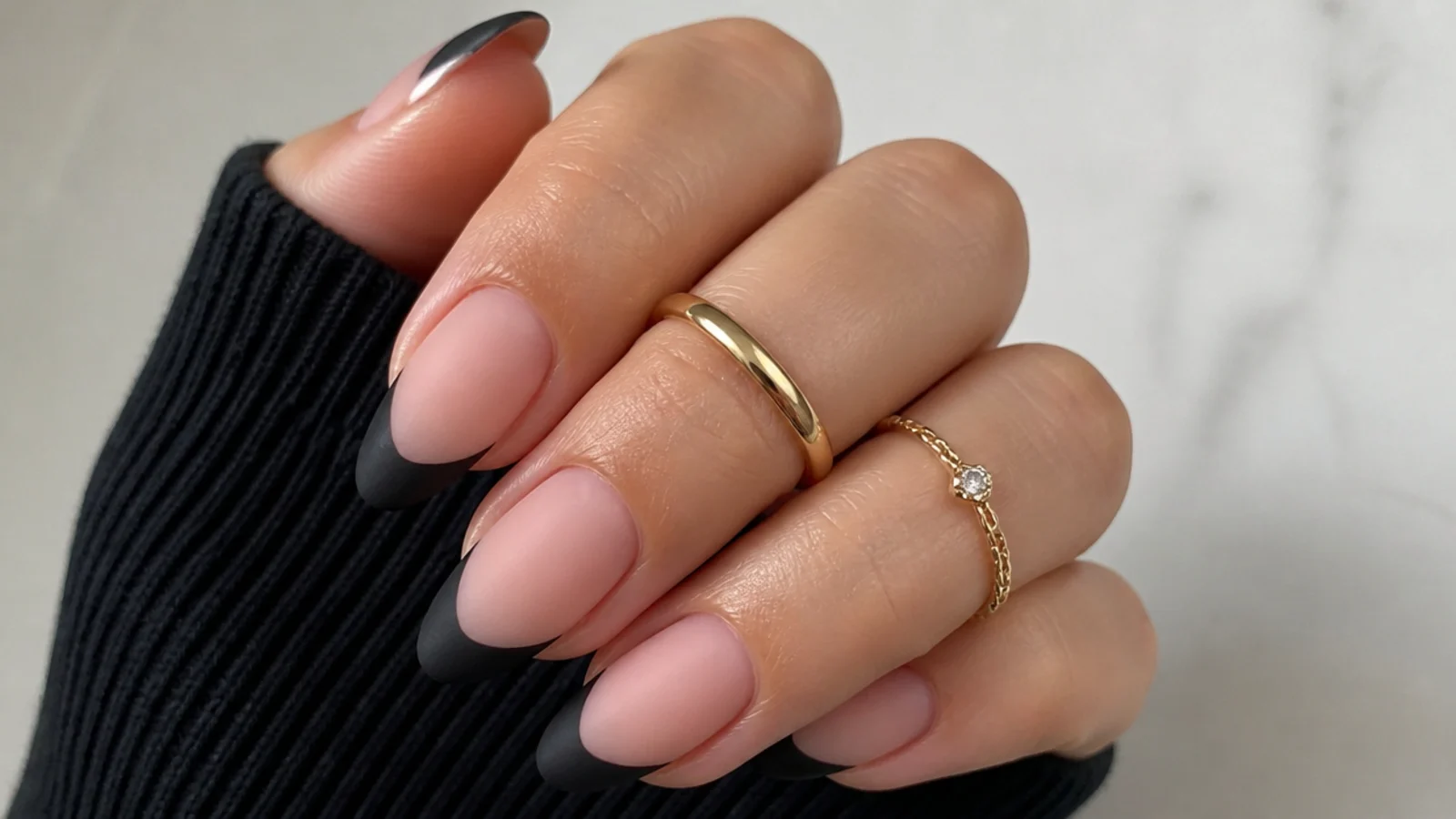 Almond nails with matte black French tips over a nude matte base