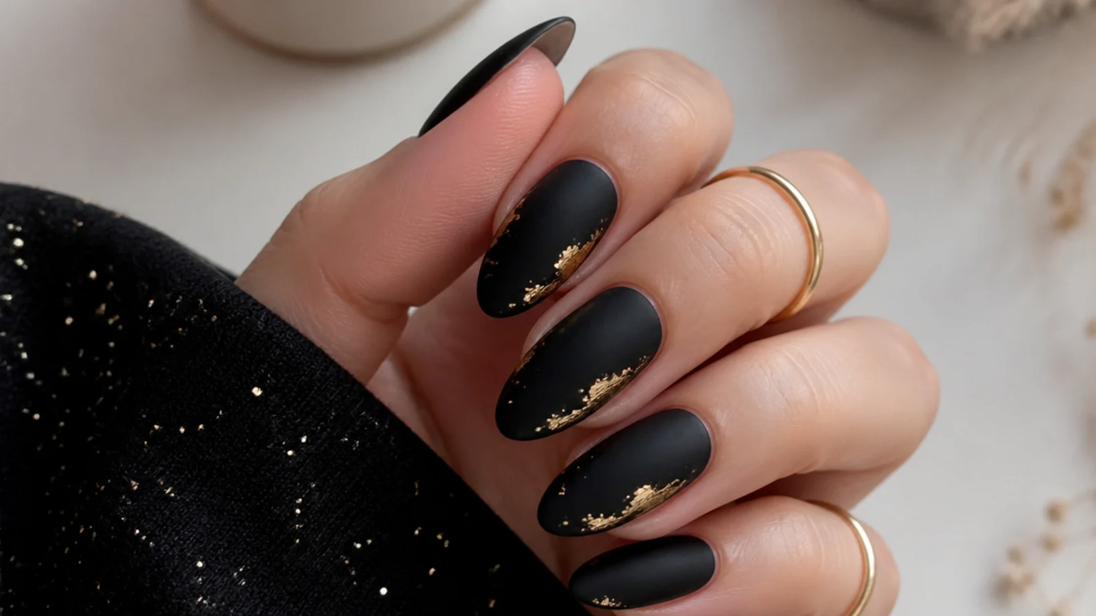 Matte black nails with thin gold foil flakes as an accent