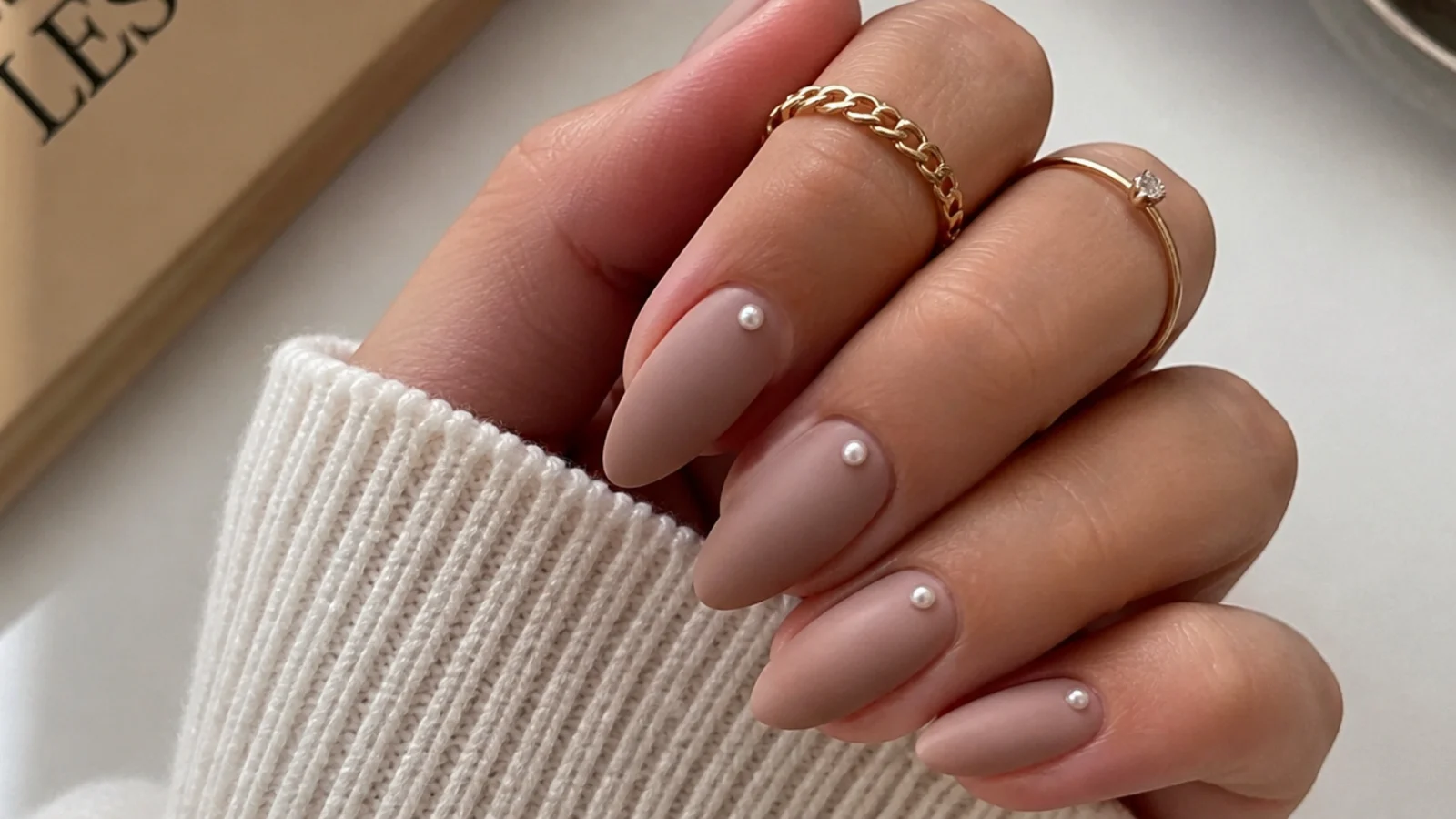 Matte nude nails with tiny pearl accents near the cuticle