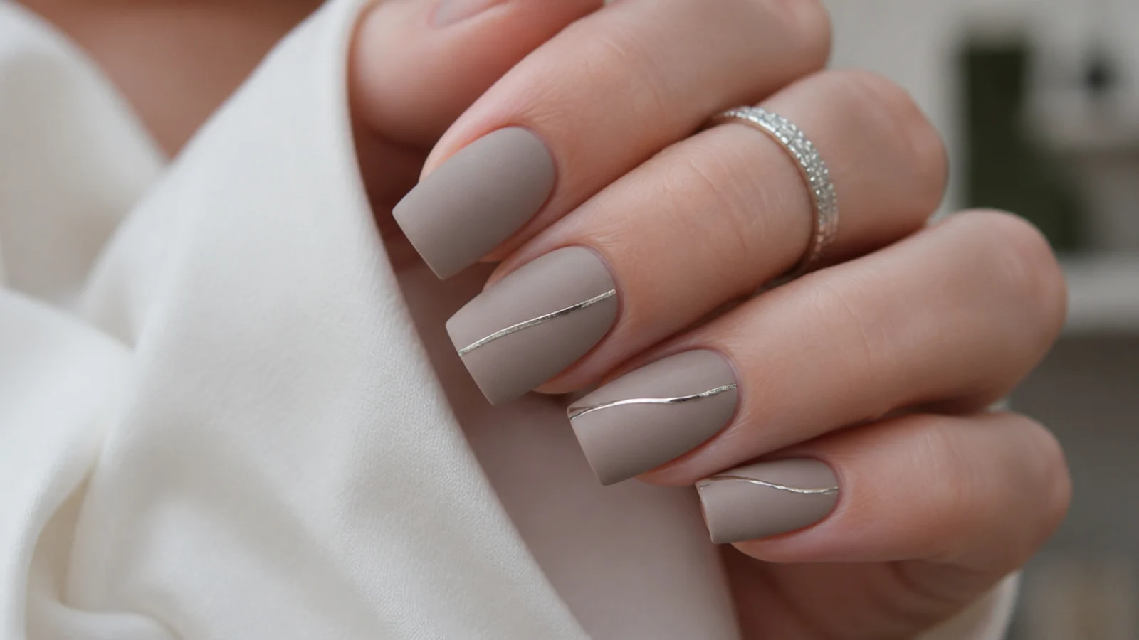 Matte greige nails with a thin silver chrome accent line