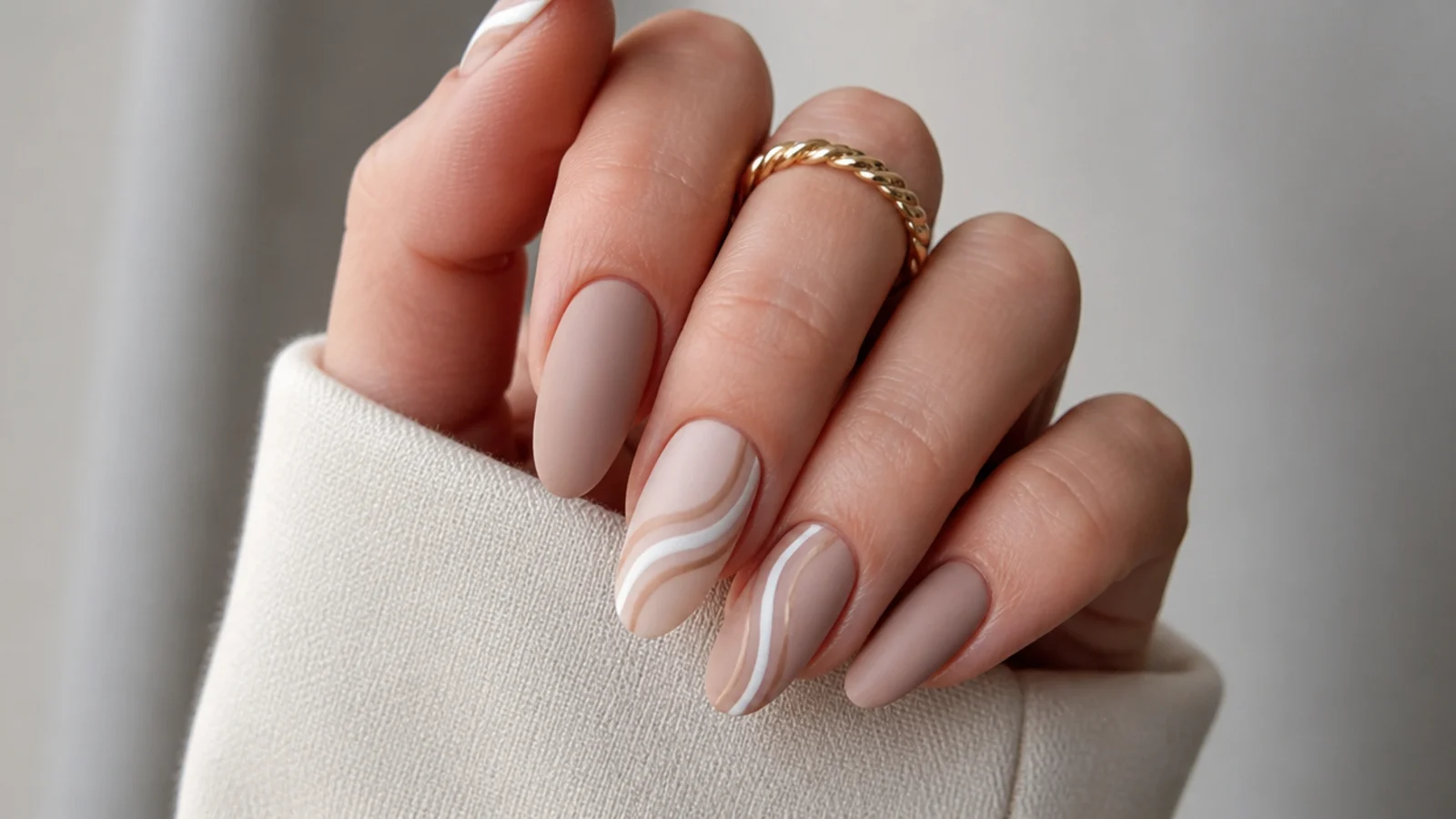 Matte nude nails with a soft tonal beige and white swirl accent