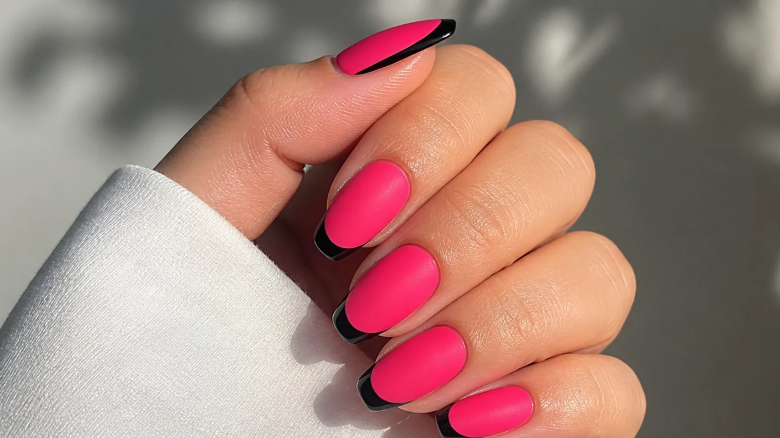 Matte hot pink nails with a thin glossy black French tip