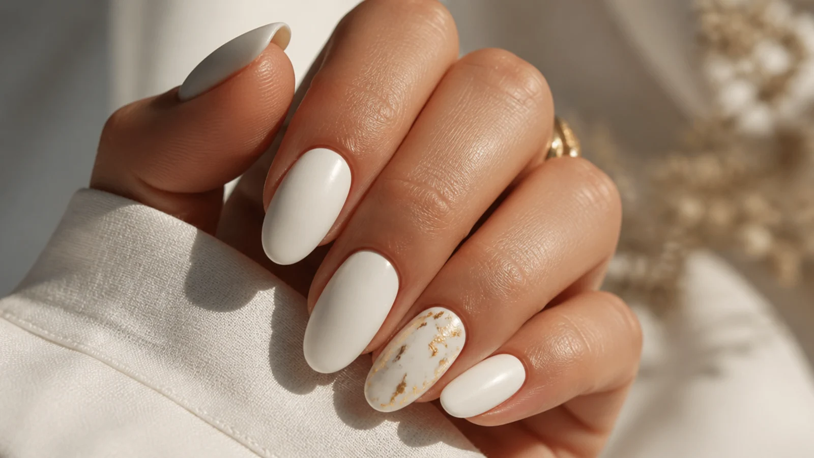 Matte white nails with thin gold foil flakes on one accent nail